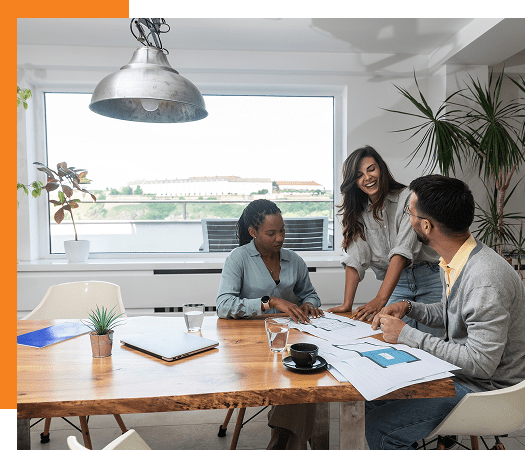 Three colleagues collaborating around a wooden table in a bright office.